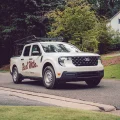 White Ford pickup truck with 'Red Mtn. Pest & Termite' logo, pest control service vehicle on tree-lined suburban street