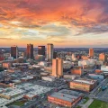 Aerial view of downtown city skyline at dramatic orange sunset with modern high-rises and city blocks