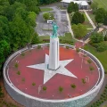 Aerial view of Statue of Liberty replica on tall column centered in circular plaza with white star and American flag