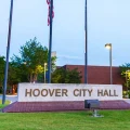 Hoover City Hall sign with American flags, flagpoles and municipal building at dusk
